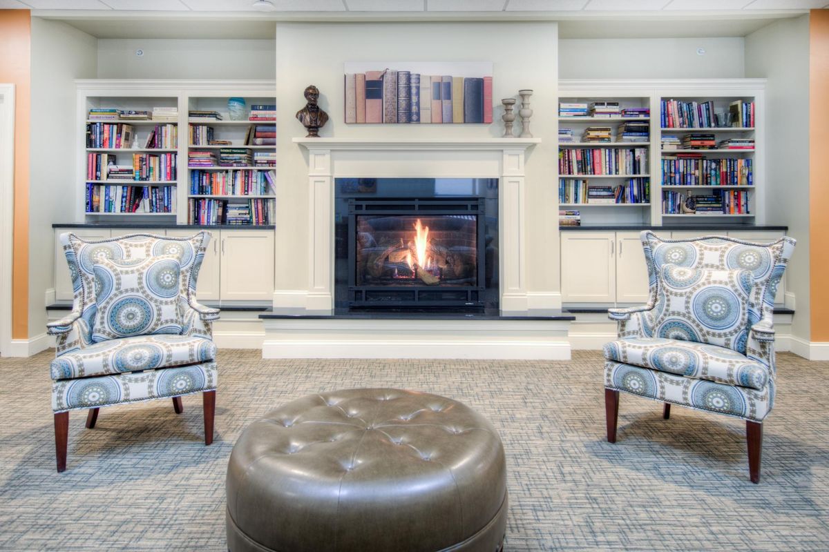 A cozy living room with a warm fireplace and bookshelves.