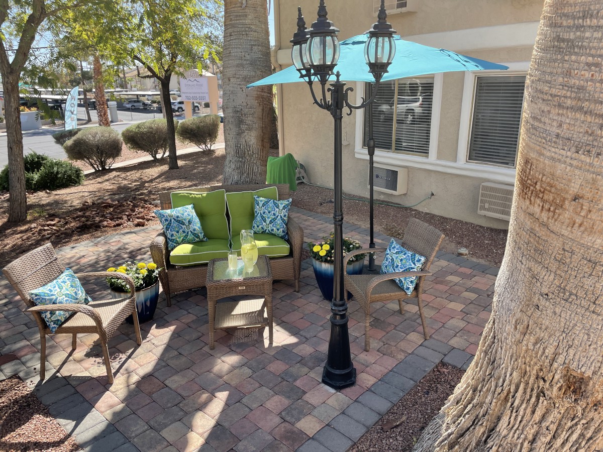 A cozy patio setup with wicker chairs, a bright umbrella, and a classic lamp post.