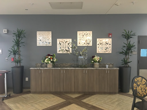 A modern lobby featuring a wooden reception counter, decorative wall art, and lush indoor plants.