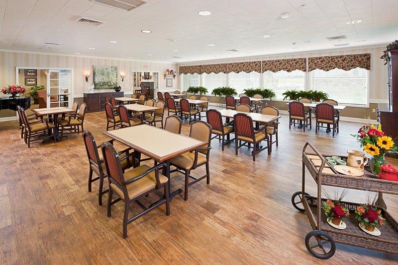 A spacious dining room with neatly arranged tables and chairs, featuring a warm wooden floor and elegant decor.