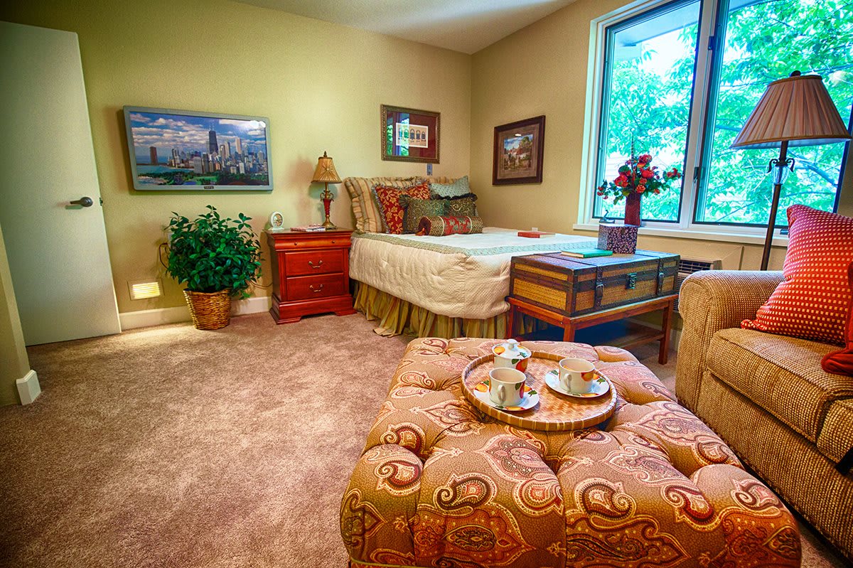 A cozy bedroom with elegant decor, featuring a bed, wooden furniture, and warm lighting.