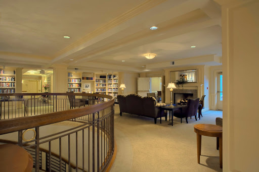 A spacious and inviting living room with a library area, featuring comfortable furniture and a warm fireplace.