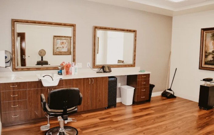 A stylish hair salon interior featuring a mirrored wall, styling chair, and wooden floors.