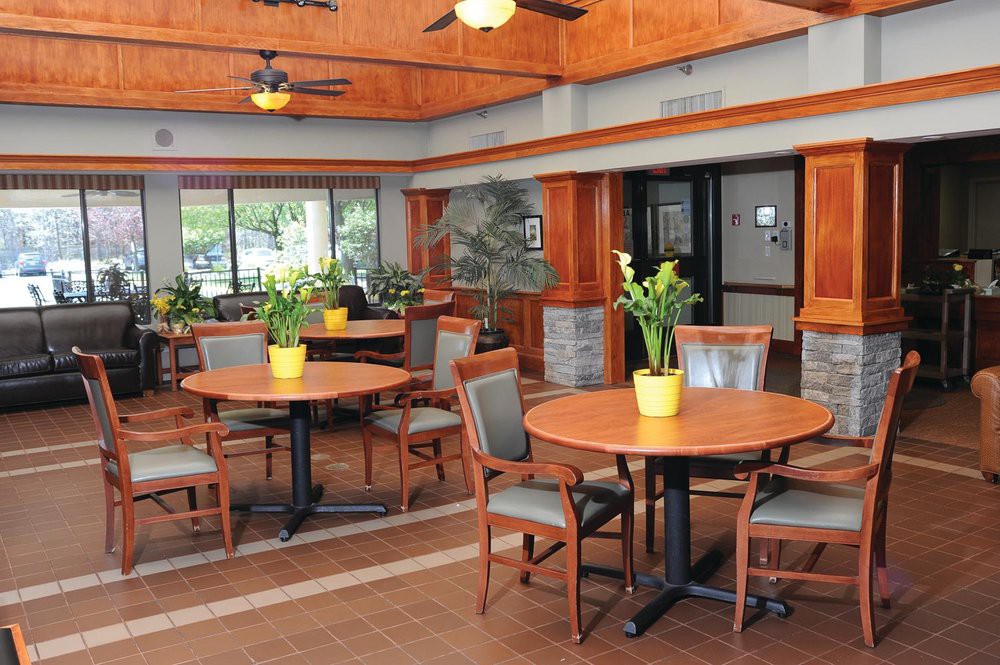 A cozy dining area with wooden tables and chairs, adorned with potted plants.