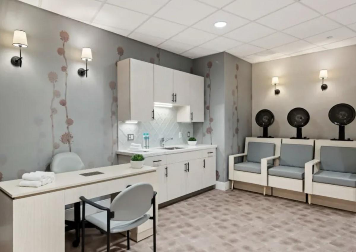 A modern salon interior with comfortable seating and hair drying stations.