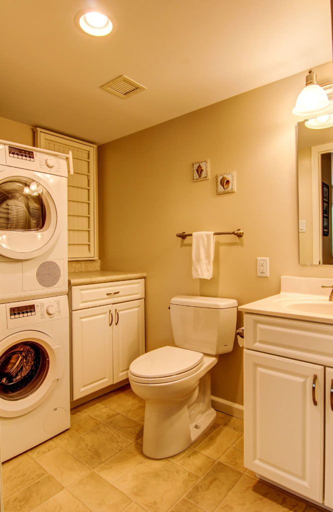 A bathroom with a stacked washer and dryer unit next to a toilet and sink.