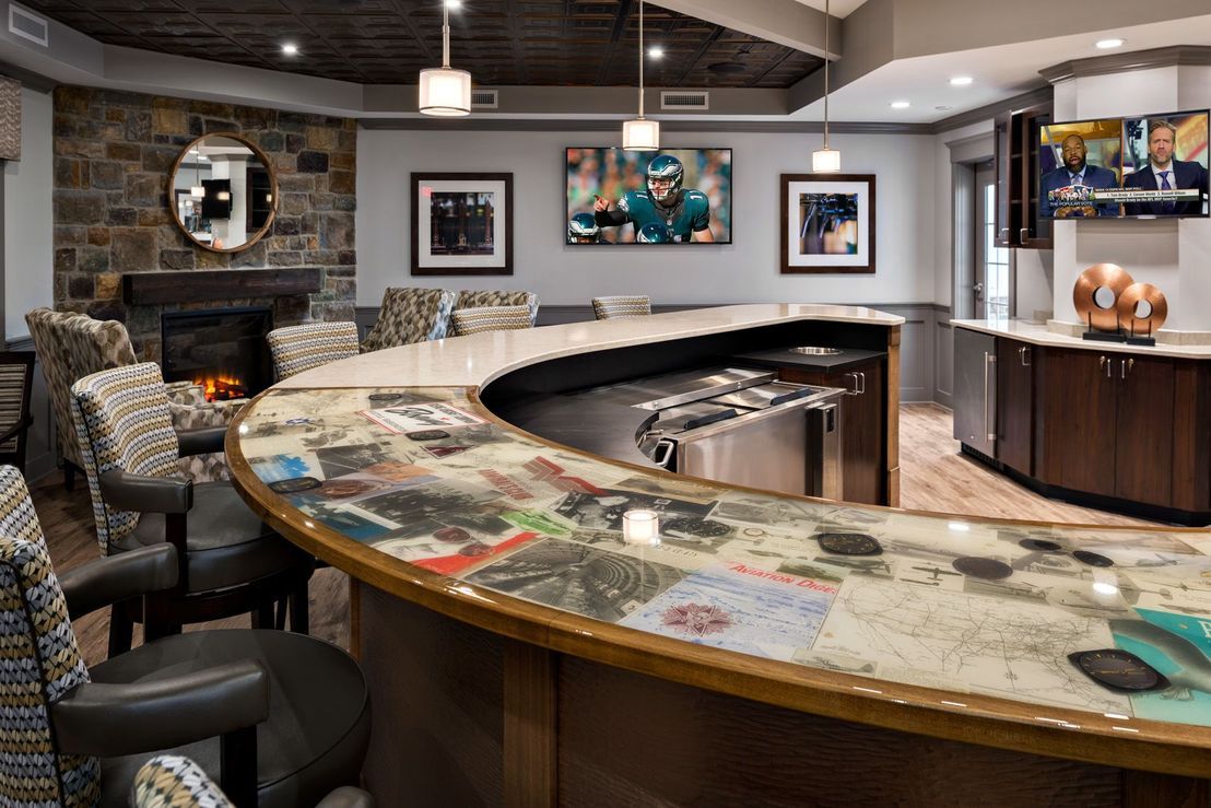 A modern bar interior featuring a curved counter with seating and decorative artwork on the walls.
