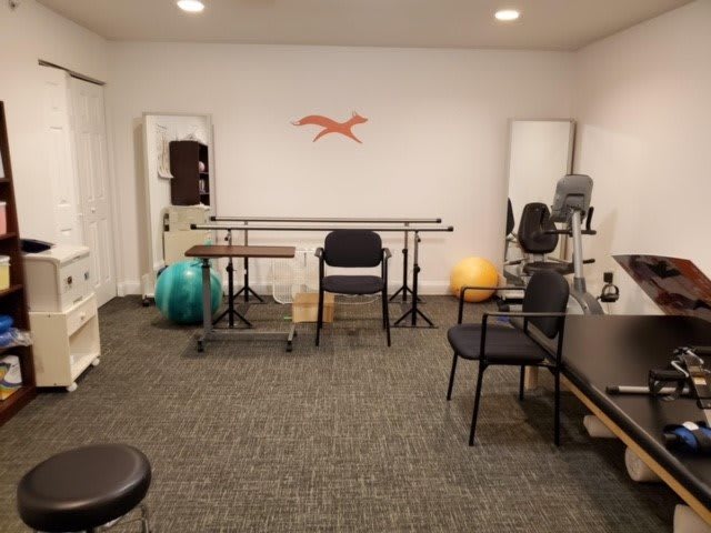 A physical therapy room equipped with exercise tools and seating.