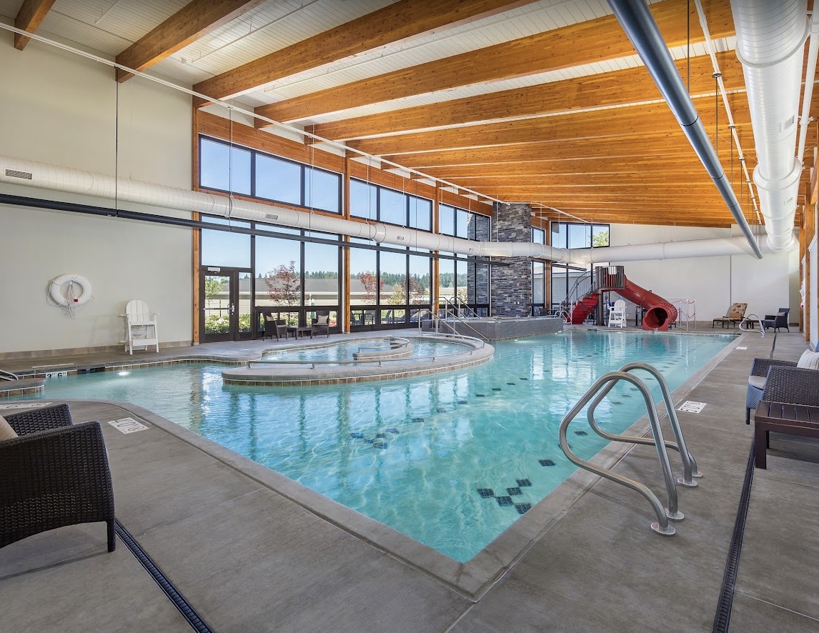 An indoor swimming pool with a water slide and ample natural lighting.