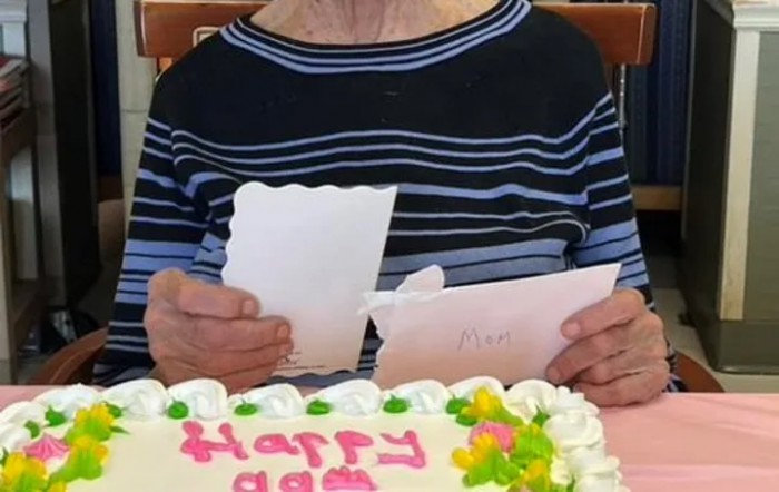 An elderly person celebrating a birthday with a cake and cards.