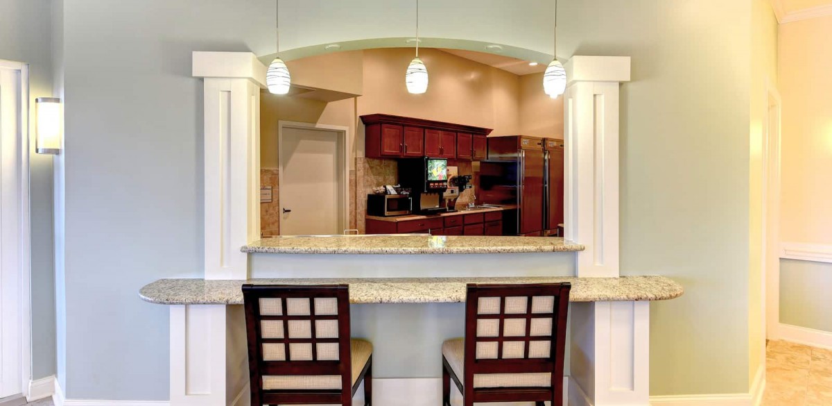 A modern kitchen with bar seating and pendant lighting.