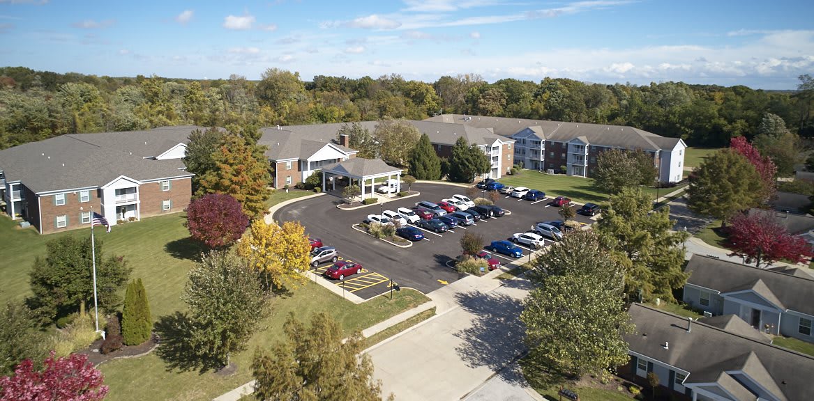 Aerial view of a residential building with a parking lot surrounded by trees.