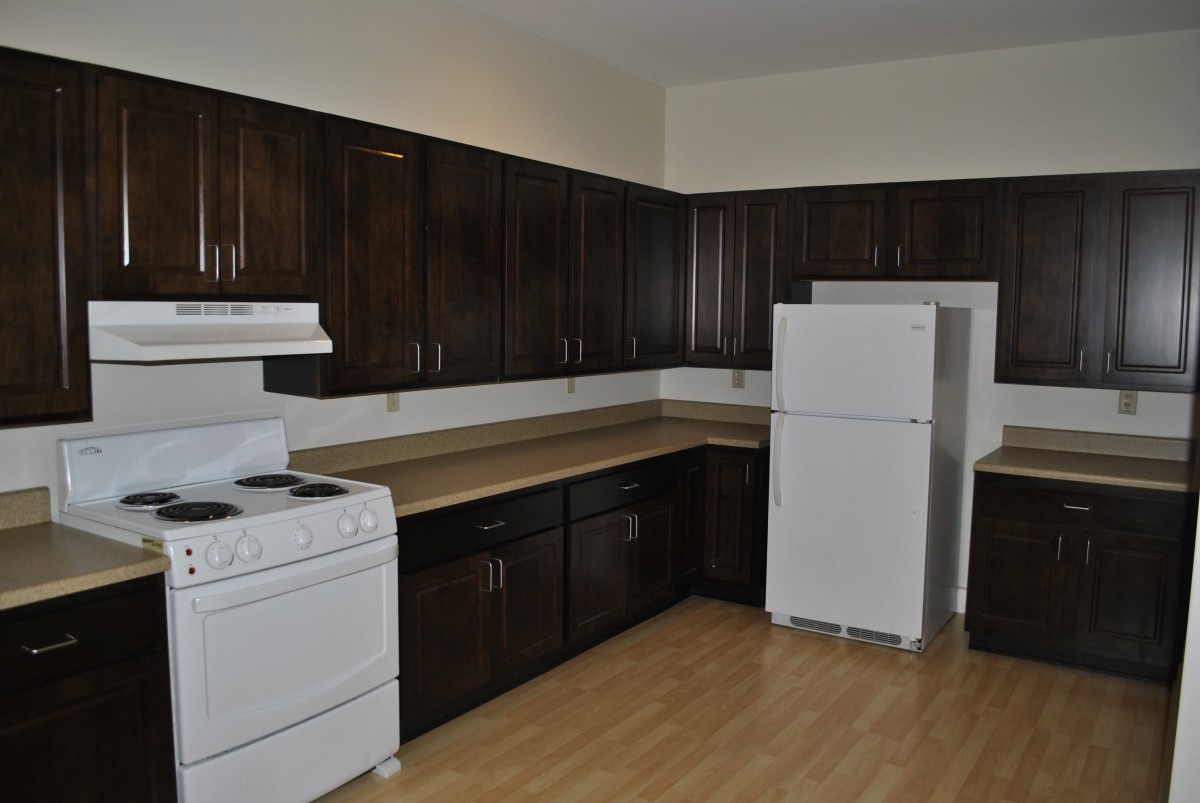 A kitchen with dark wood cabinets, a white stove, and a refrigerator.