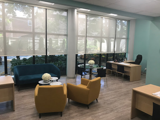 A modern office space featuring comfortable seating and large windows allowing plenty of natural light.