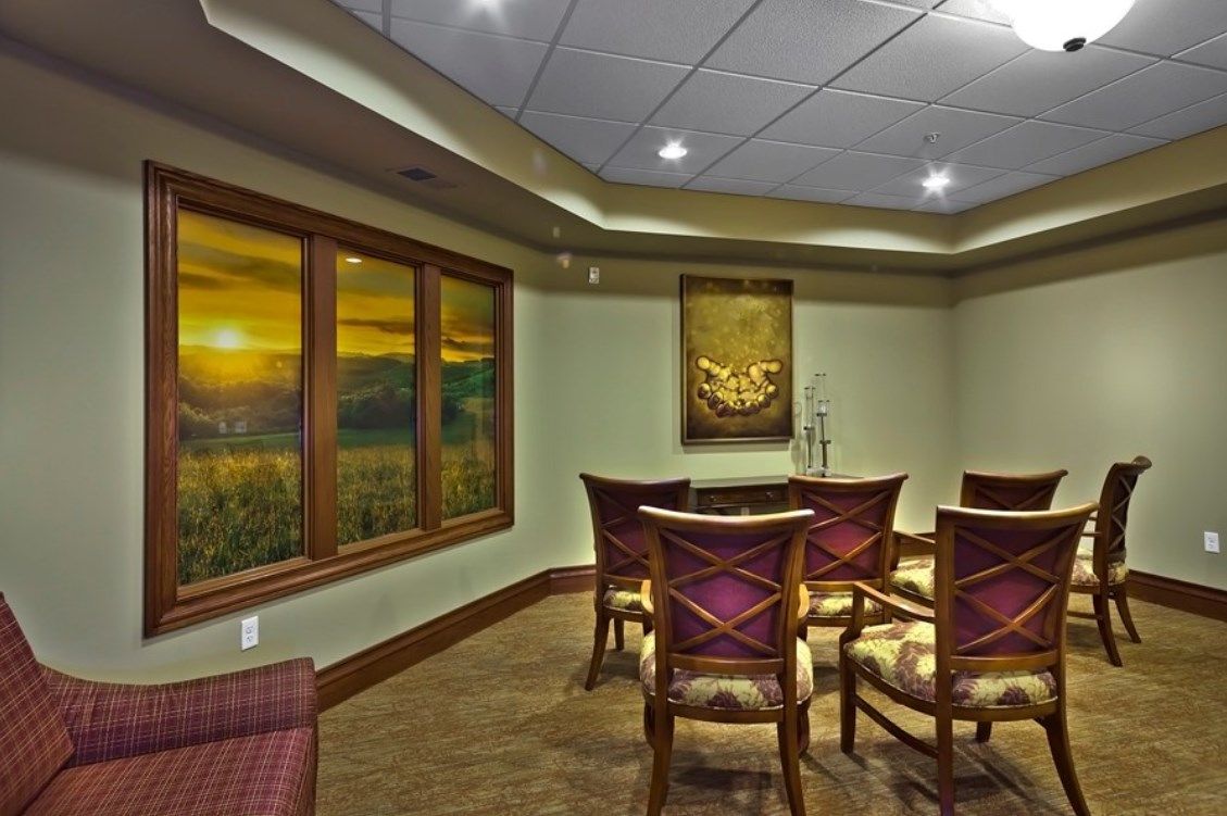 A well-decorated conference room with chairs arranged around a table, featuring a scenic window view and artwork on the wall.