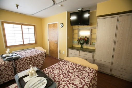 A cozy room with two beds, decorated in warm colors and equipped with a television.