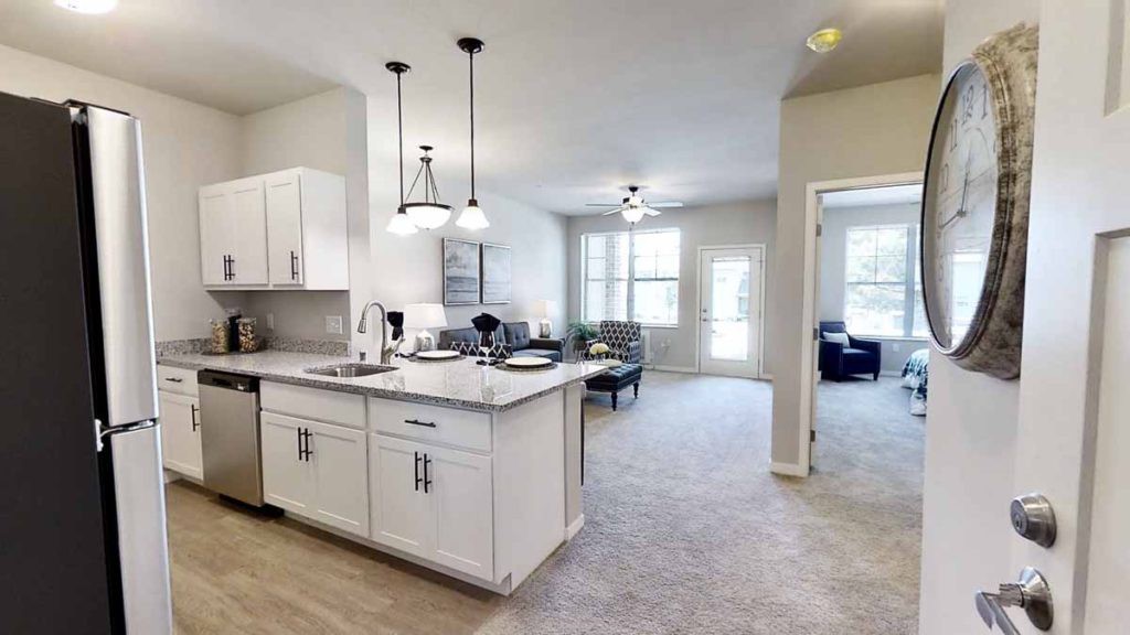A modern open-concept apartment with a white cabinet kitchen and a spacious living area.