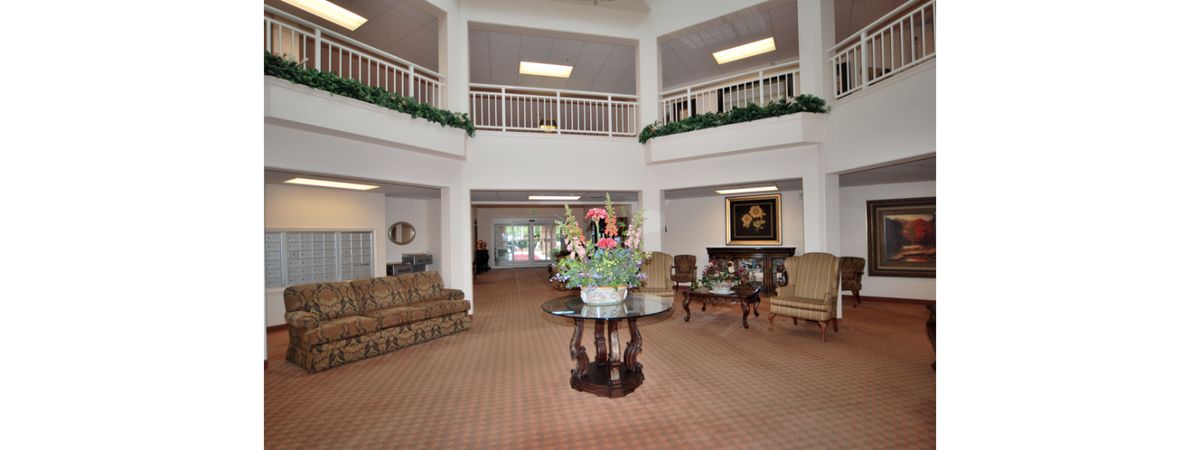 A spacious lobby area with sofas, a central table adorned with flowers, and a balcony overlooking the space.