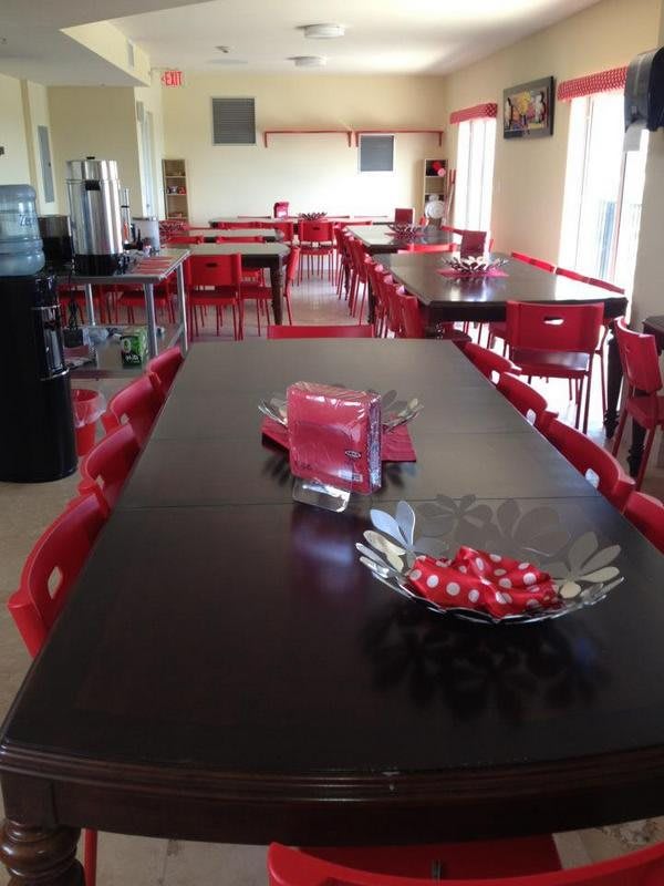 A cozy cafe with red-themed decor, featuring neatly arranged tables and chairs.