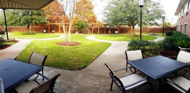 A peaceful backyard garden with a patio, surrounded by trees and a well-maintained lawn.