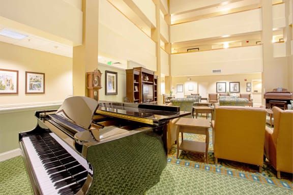 A spacious hotel lobby featuring a grand piano and elegant furnishings.