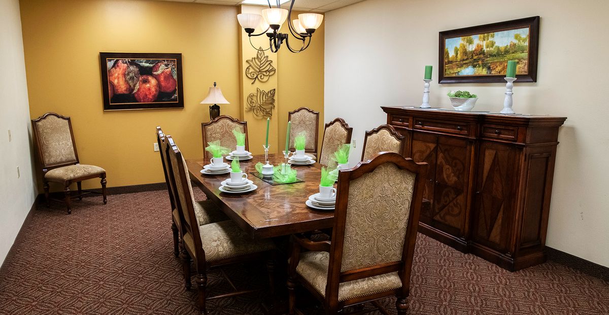 A traditional dining room with a wooden table set for six, featuring elegant decor and a chandelier.