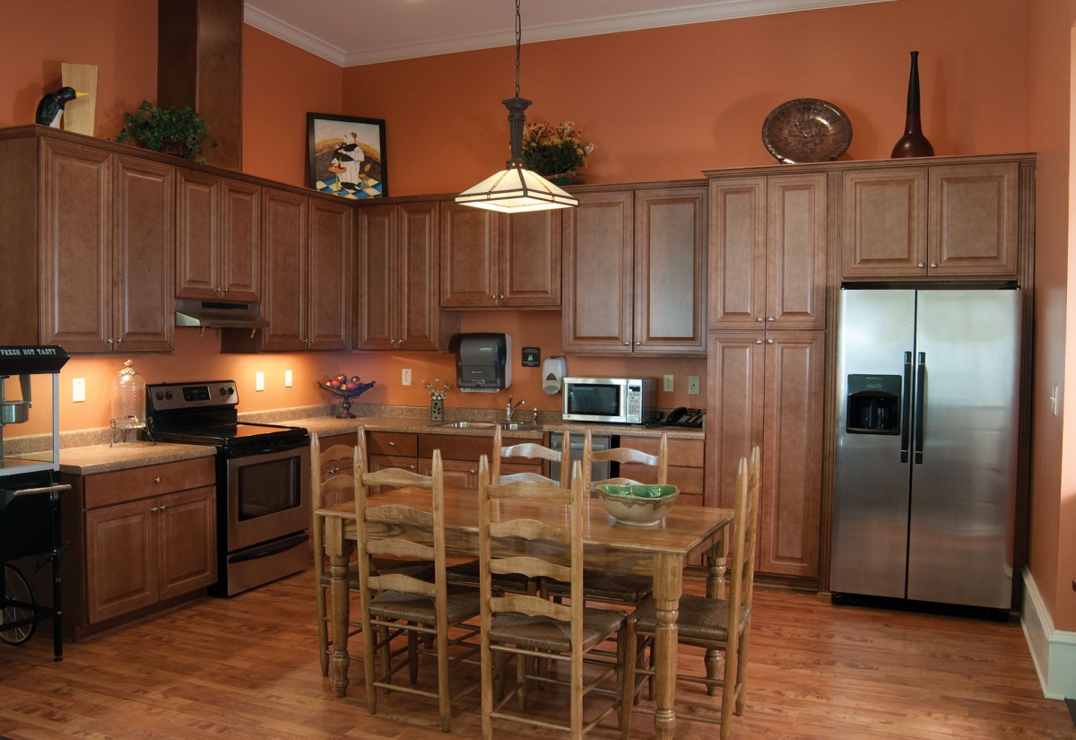 A spacious kitchen with wooden cabinets, a dining table, and stainless steel appliances.