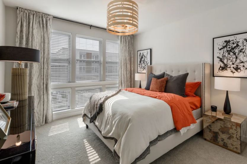 A modern bedroom with orange accent pillows and a cozy bed.