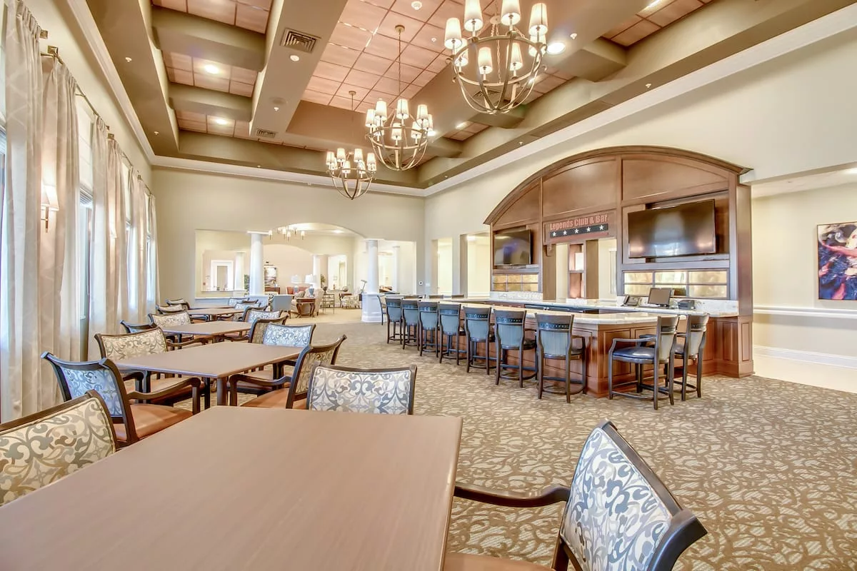 An upscale restaurant interior featuring elegant chandeliers and a spacious bar area.