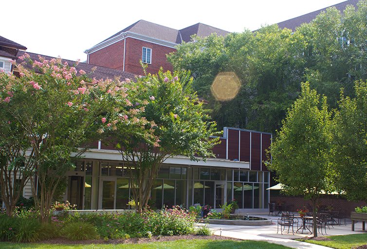 A view of a building on a campus surrounded by trees and greenery.