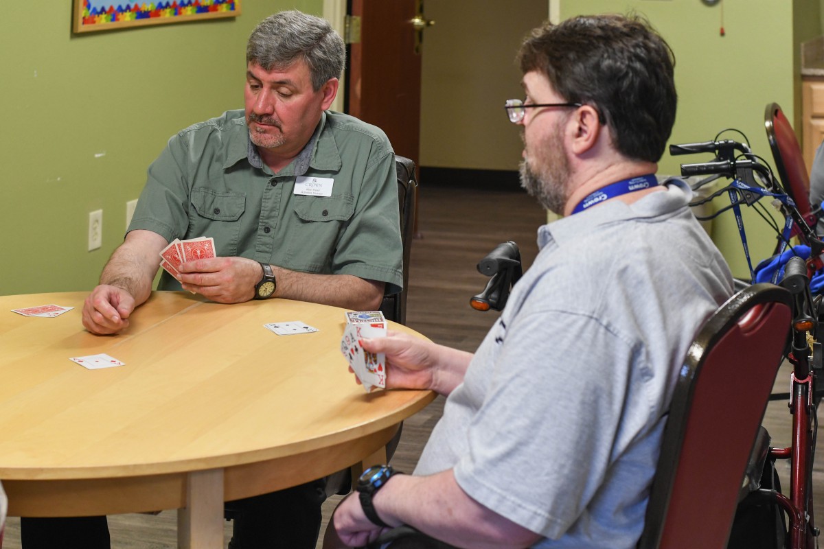 Two people sitting at a table playing cards indoors.
