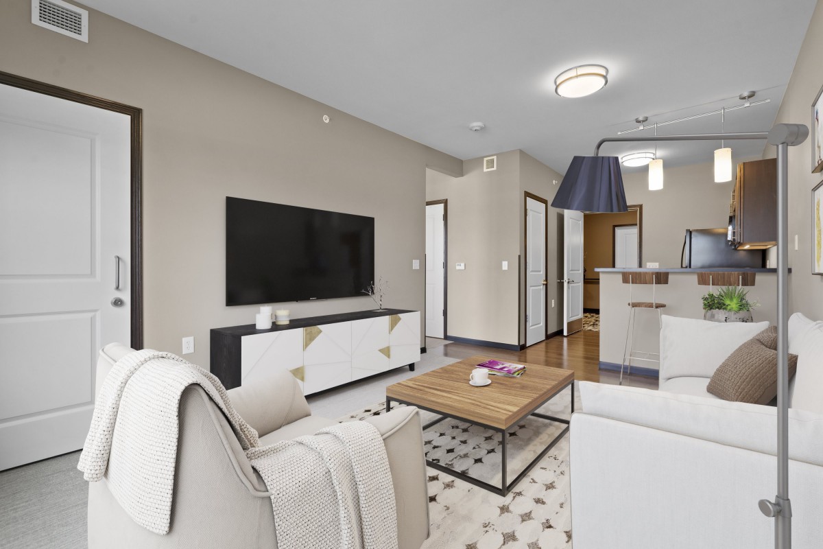 A modern living room with neutral tones, featuring a sofa, coffee table, and wall-mounted TV.