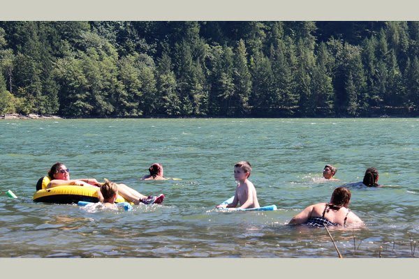 People enjoying a swim in a scenic lake surrounded by lush green trees.