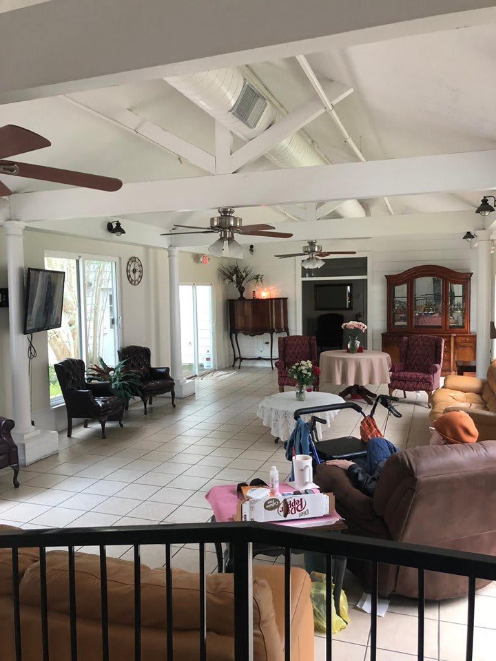 A spacious living room with ceiling fans, comfortable seating, and a television.