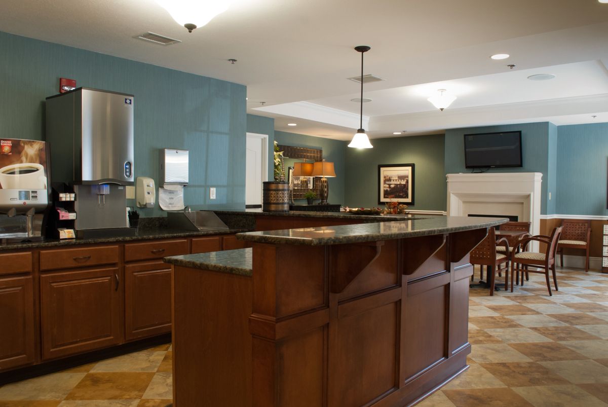 A modern kitchen with a bar counter, featuring wooden cabinetry and pendant lighting.