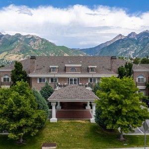 A large house with a mountainous backdrop and lush greenery.