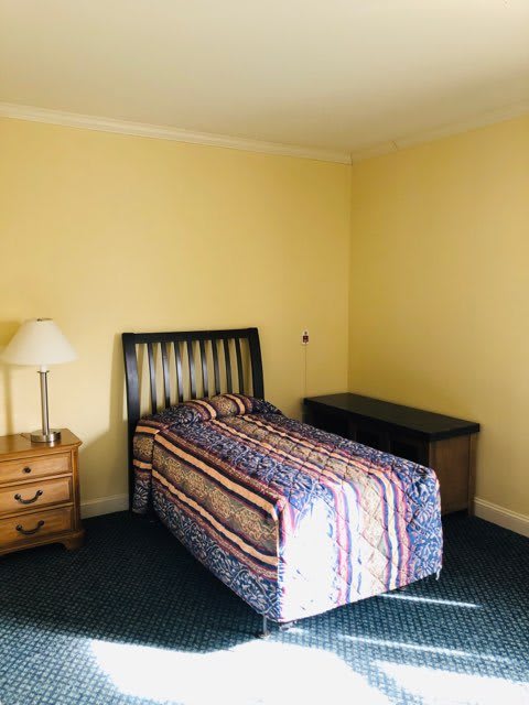 A minimalist bedroom with a single bed and basic furnishings.