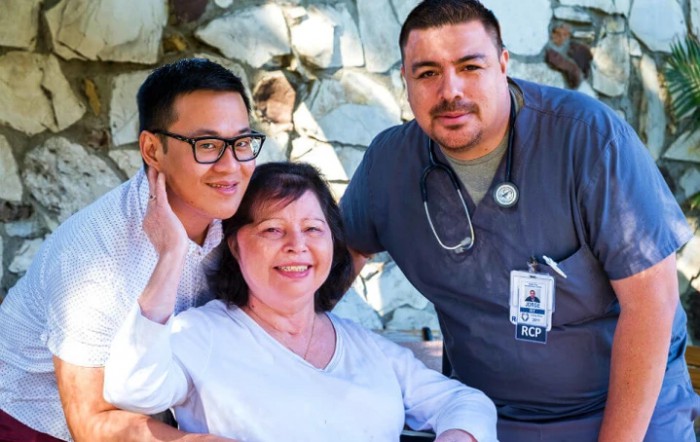 A group of healthcare professionals with a patient, all smiling.