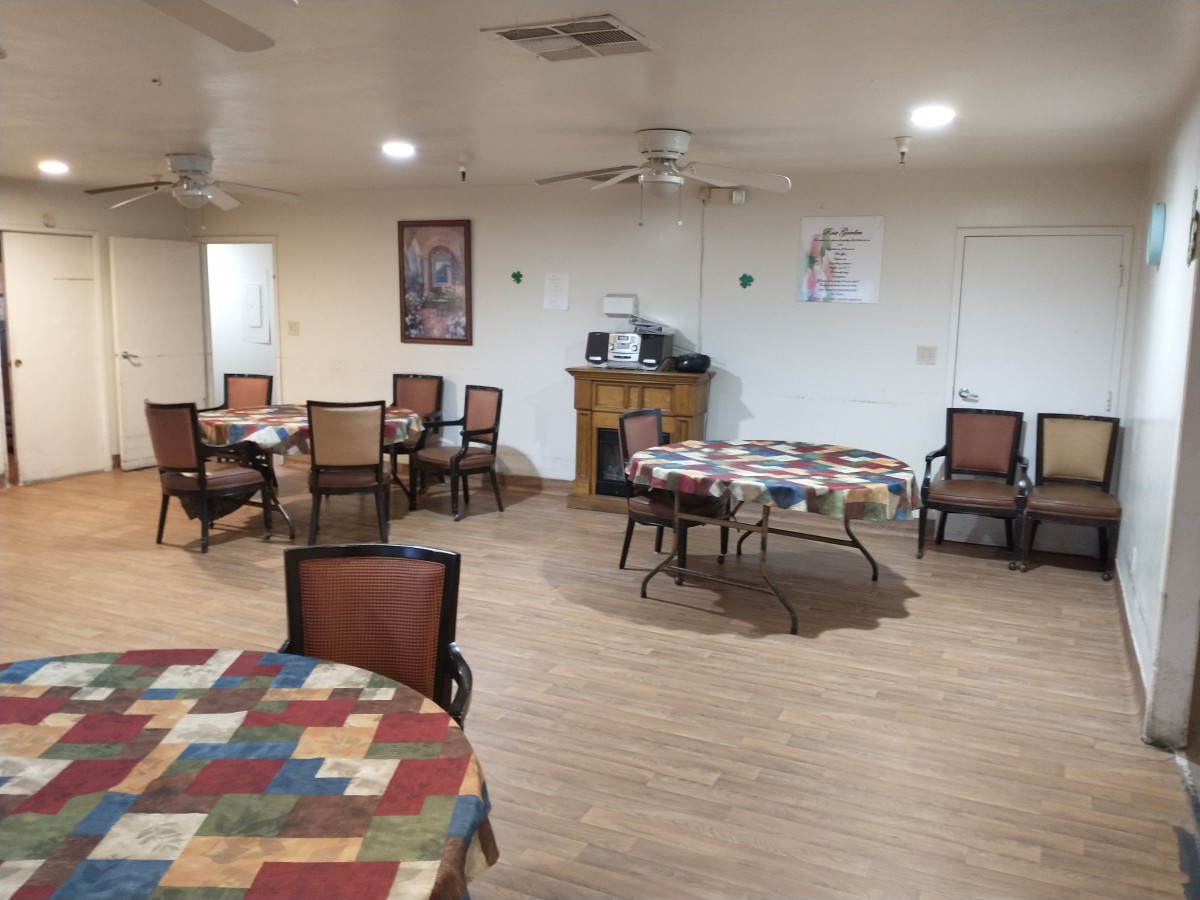 A spacious dining area with several tables and chairs arranged neatly, featuring colorful table covers and wall decorations.