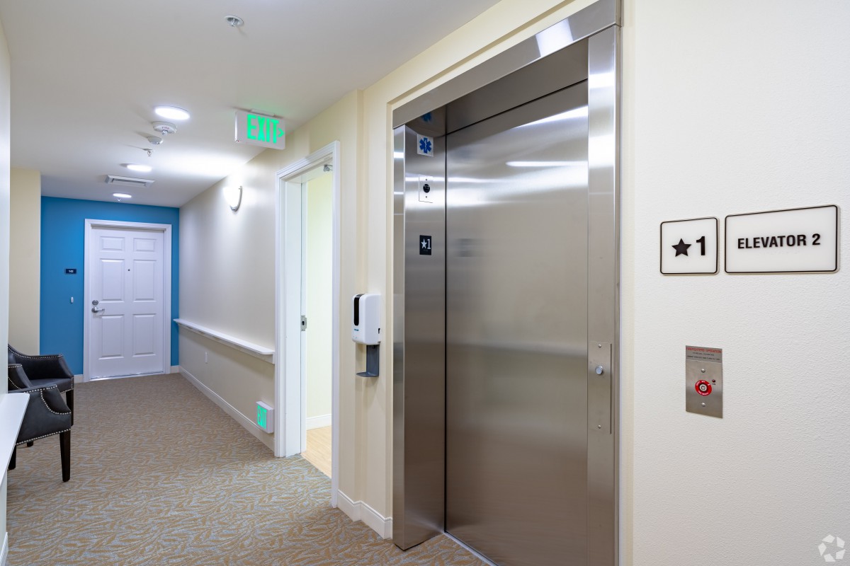 A modern building hallway with an elevator and bright lighting.