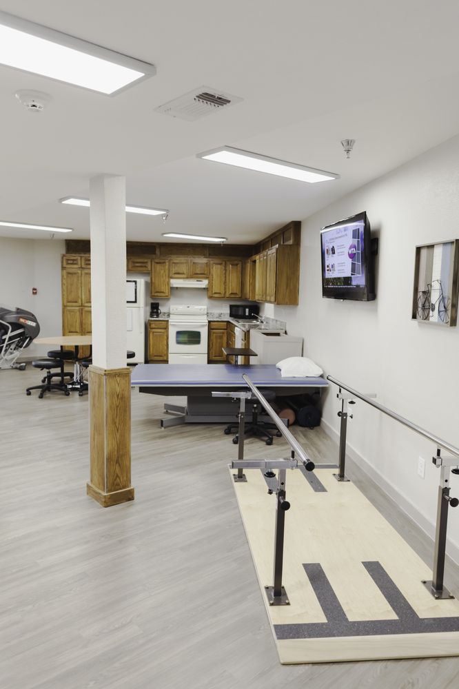 Therapy and rehabilitation room equipped with exercise machines and parallel bars.