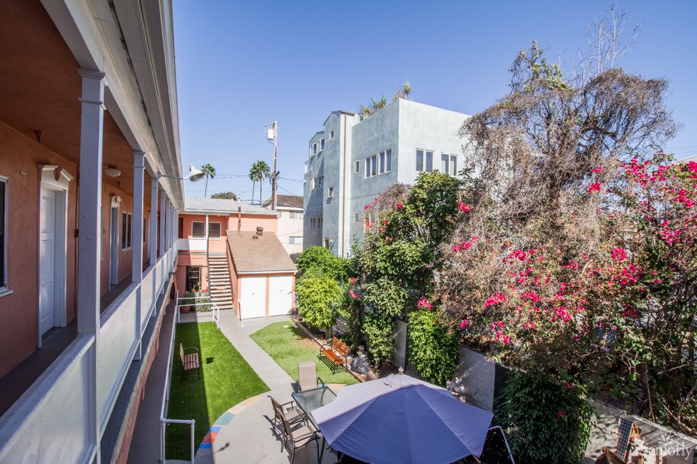 A sunny courtyard with a garden, patio furniture, and surrounding buildings.
