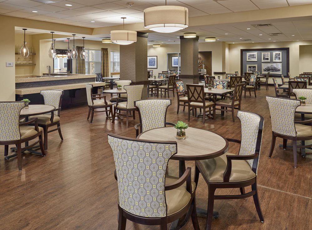 A spacious dining area with elegant chairs and tables, featuring ambient lighting and a wooden floor.