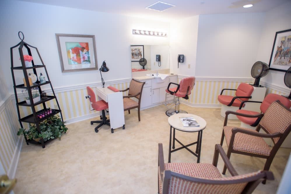 A cozy salon interior with comfortable seating and a well-lit mirror.