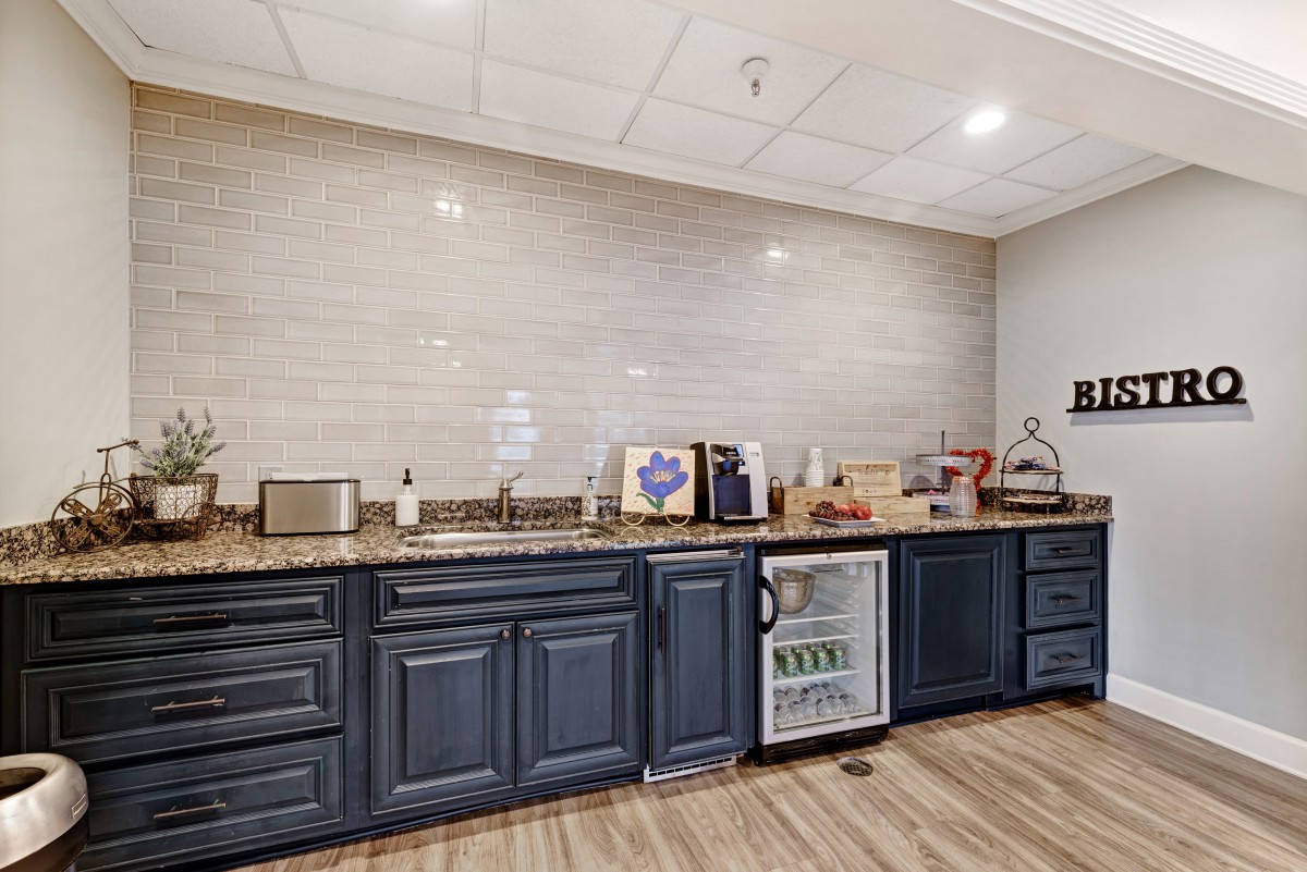 A modern kitchen with dark cabinets, a countertop with appliances, and a mini fridge.