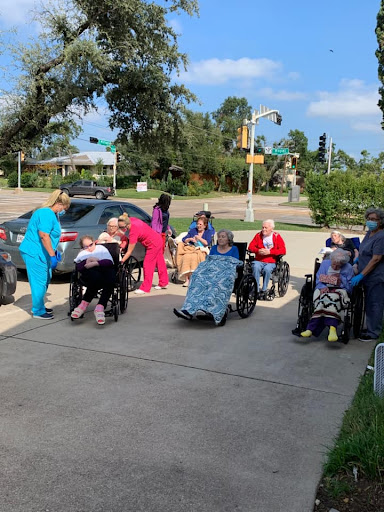 A group of seniors enjoying time outside with caregivers, creating a vibrant community atmosphere.