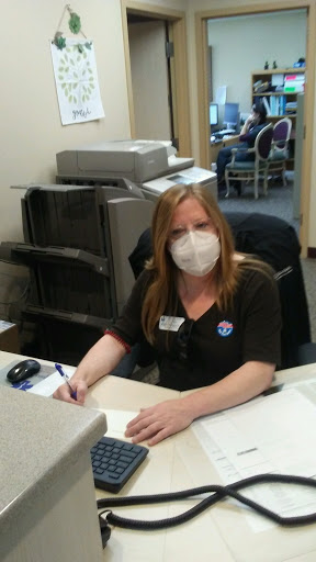 A woman wearing a mask diligently working at an office desk.