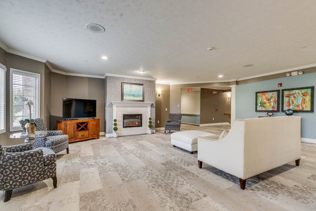 A spacious and elegantly designed living room with modern furnishings, centered around a fireplace and television.