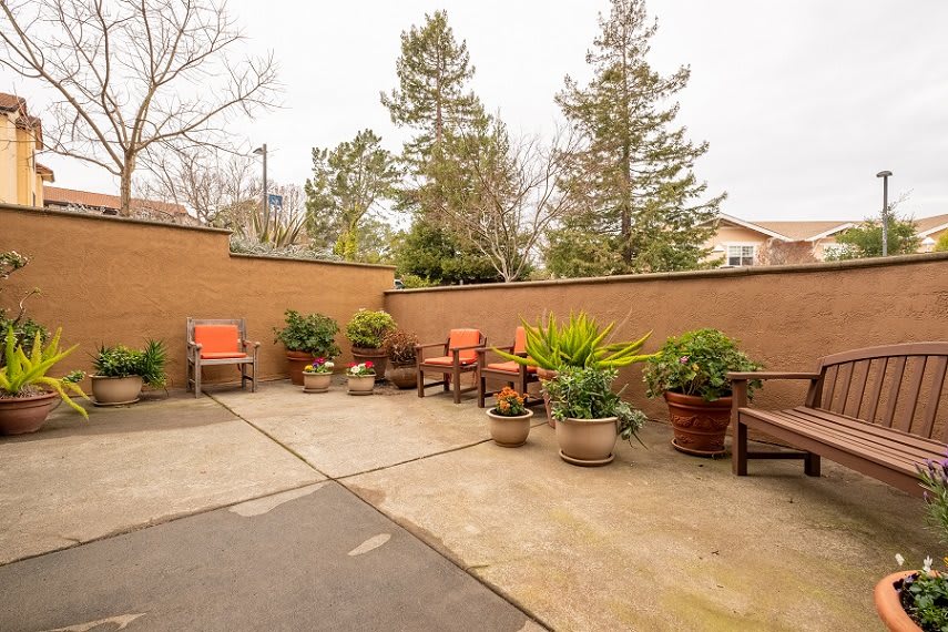 A cozy outdoor patio with seating and potted plants.