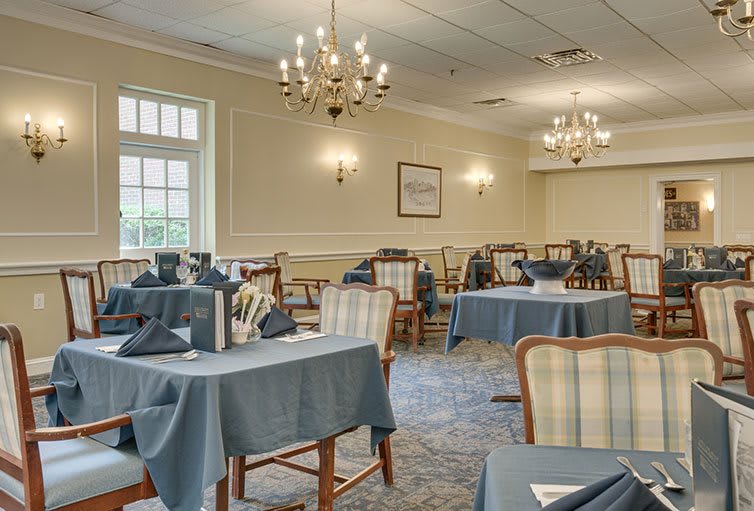 Elegantly set dining room with chandeliers and neatly arranged tables.